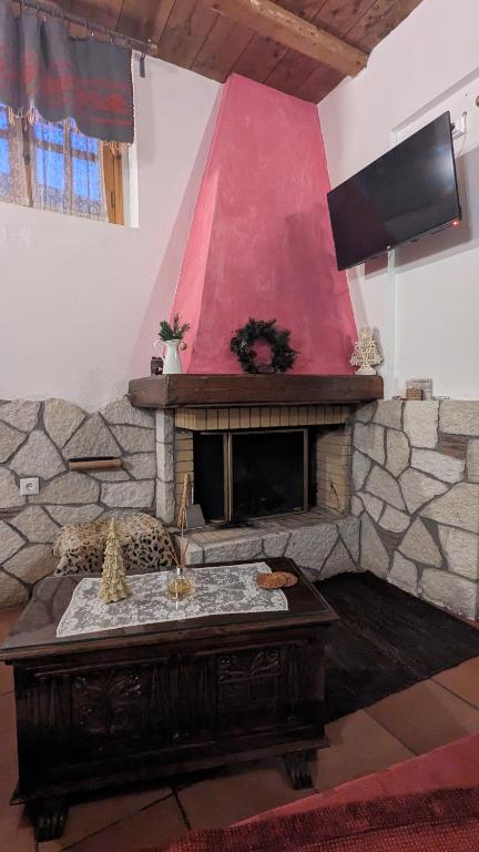 salon z kamiennym kominkiem i czerwoną ścianą w obiekcie Diminio 3 Apartment at Livadi Arachova w mieście Arachova