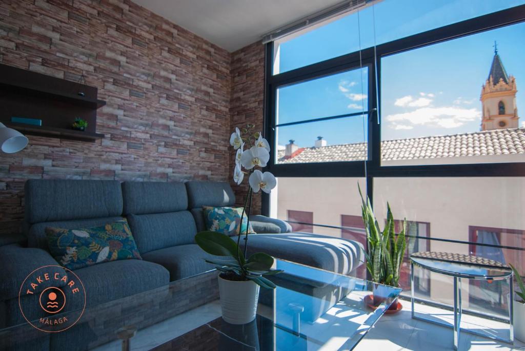 een woonkamer met een blauwe bank en een bakstenen muur bij Apartment with terrace in Malaga Center - TCM in Málaga