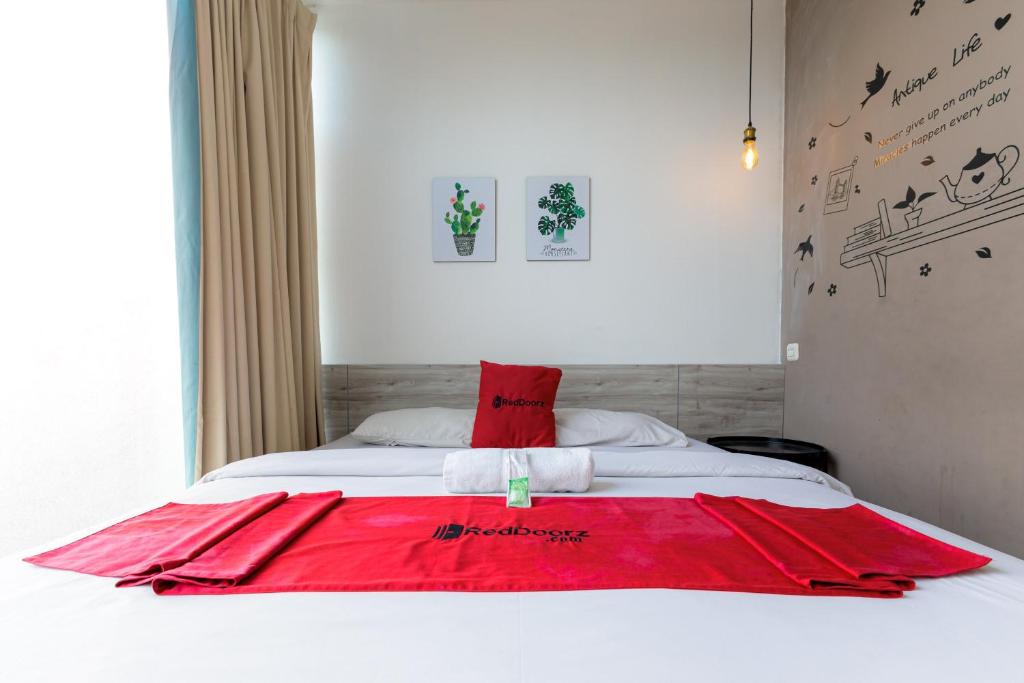 a bed with a red blanket on top of it at RedDoorz near Mangga Dua Mall in Jakarta