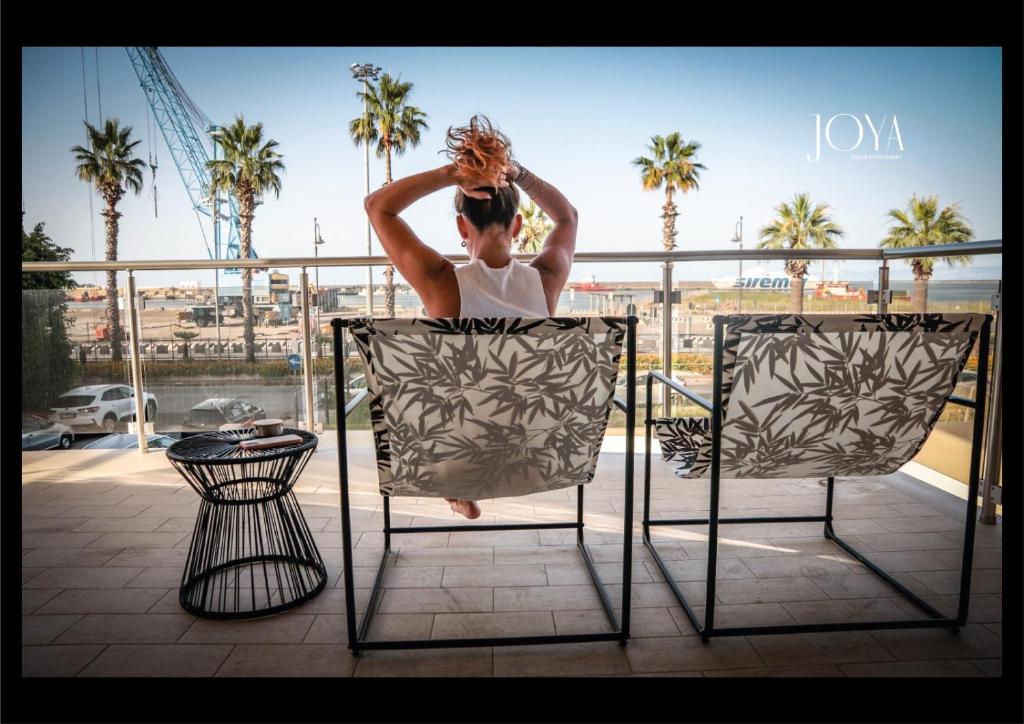 a woman sitting in a chair on a balcony at Joya Apartment's - Milazzo in Milazzo