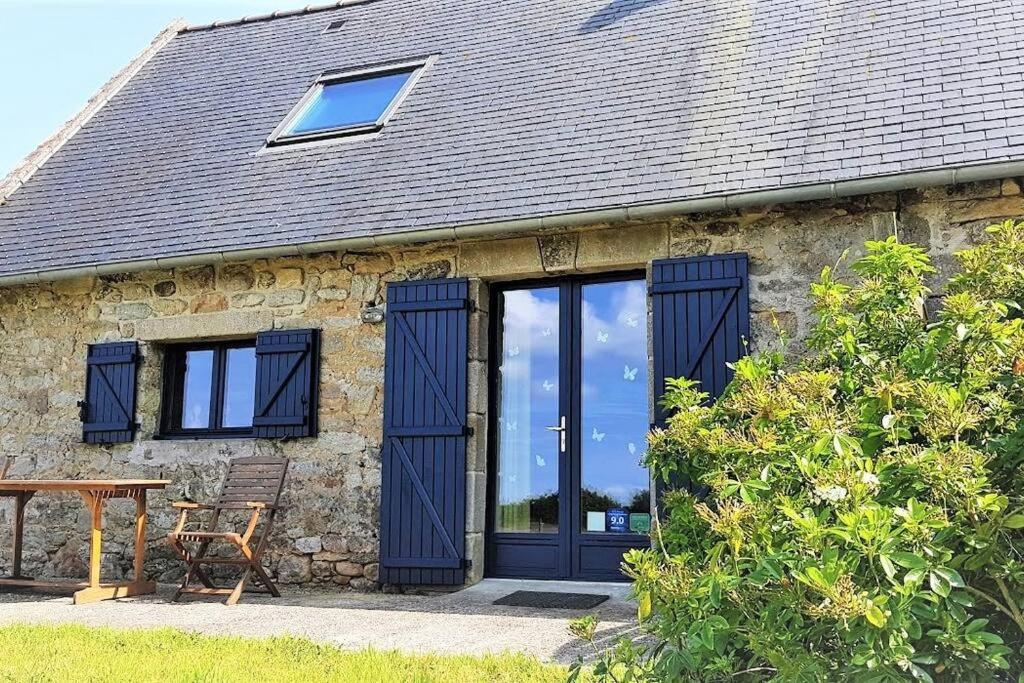 uma casa de pedra com portas azuis e uma mesa de madeira em La Clef des Champs, gîte à la ferme au pied des vignes, Finistère sud ! em Pouldergat