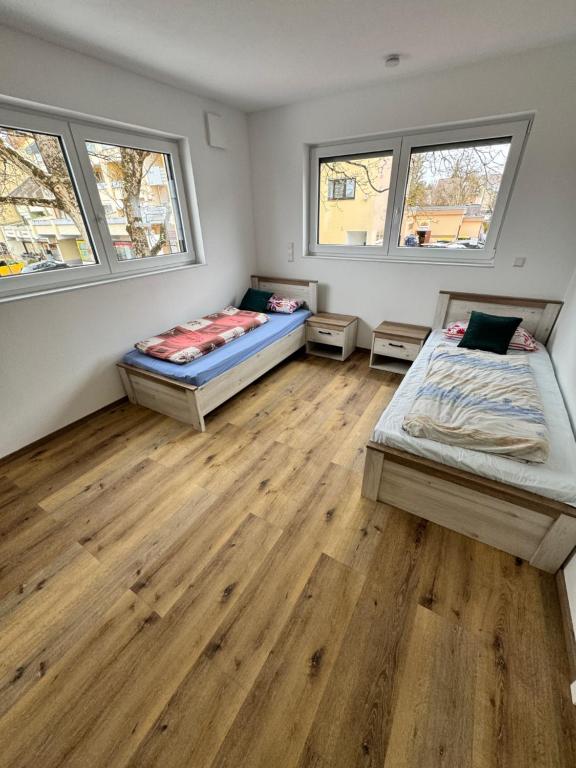 two beds in a room with wooden floors and windows at City Villa Bad Dürrheim in Bad Dürrheim