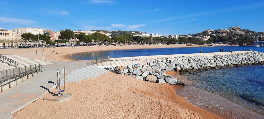 a beach with rocks and people walking on the beach at La Casa M'SOL in Sant Feliu de Guixols