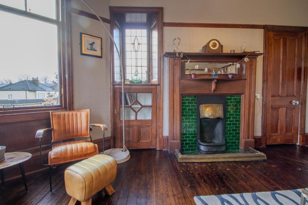 ein Wohnzimmer mit einem Kamin und einem Stuhl in der Unterkunft Pass the Keys Beautiful, traditional 2 bed flat w free parking in Glasgow