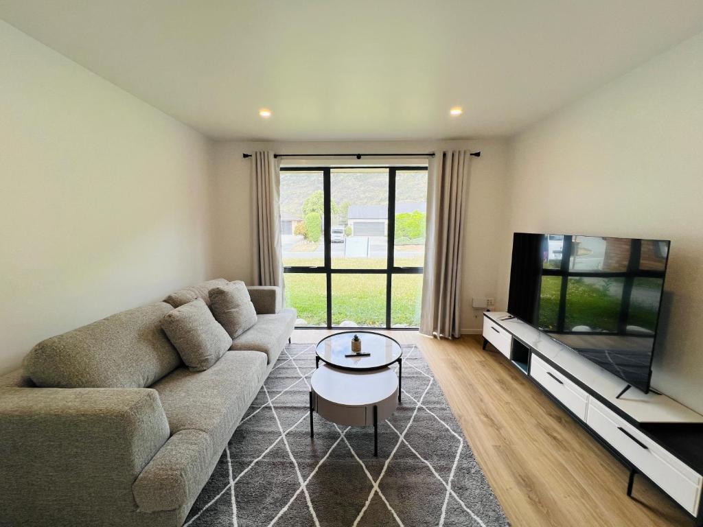 sala de estar con sofá y TV de pantalla plana en Leisure Holiday Home Lake Hayes Easte Queenstown en Arrowtown