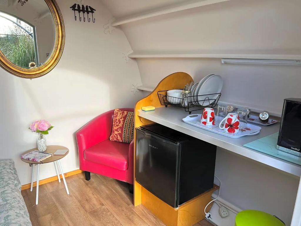a small room with a red chair and a table at Cosy 1 bedroom cabin- Moon Pod in Salisbury