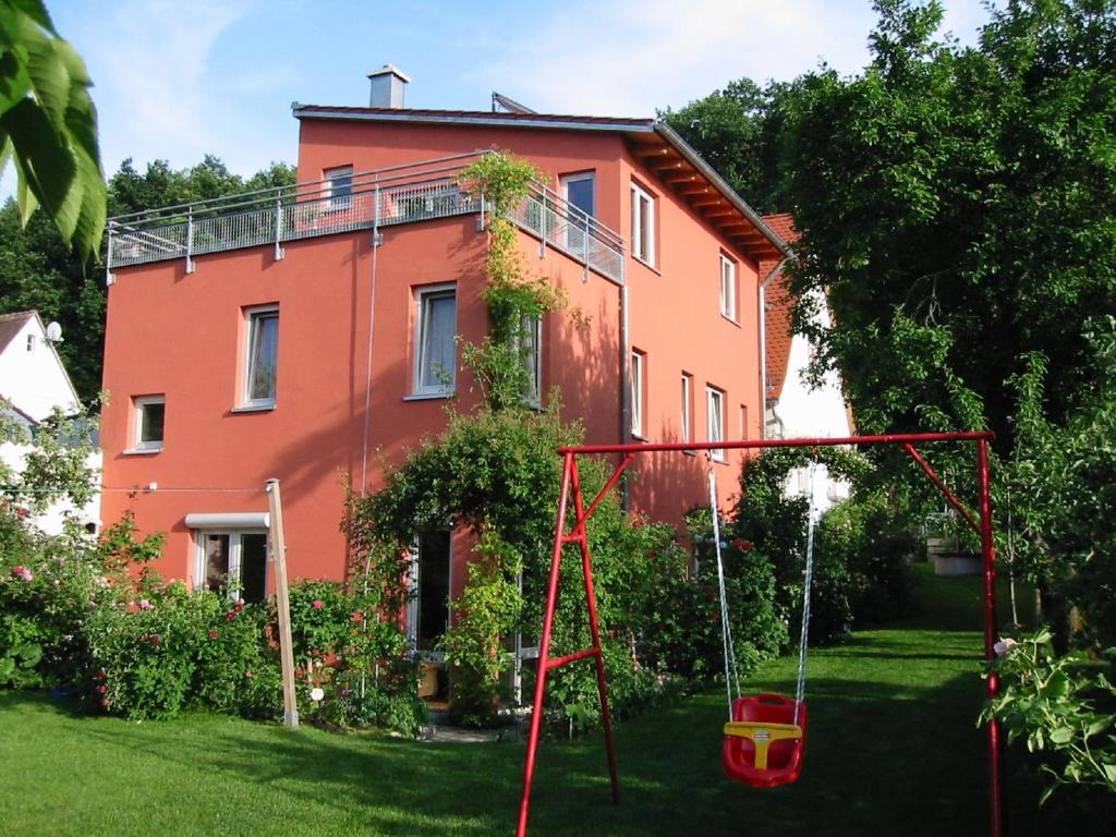 an orange house with a swing in the yard at Ferienwohnung „Rosarium“ in Gunzenhausen