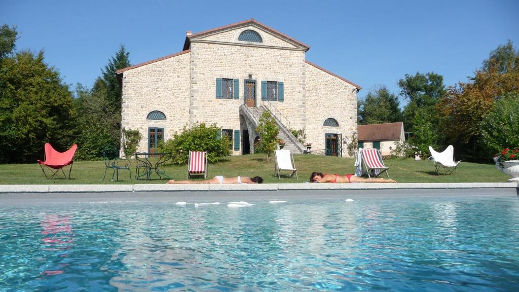 a house with a swimming pool in front of a building at Le Moulin Rénové in La Boulaye