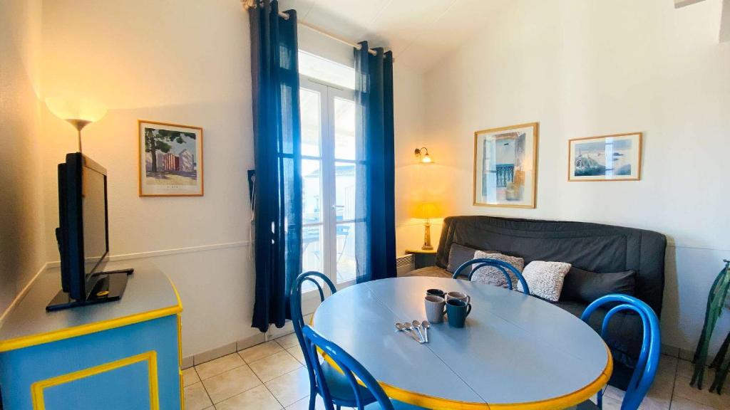 a living room with a table and a couch at Appartement dans résidence avec piscine proche plage et commerces in La Couarde-sur-Mer