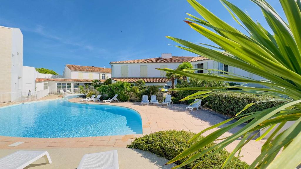 a swimming pool in a yard with chairs and a building at Appartement dans résidence avec piscine proche plage et commerces in La Couarde-sur-Mer