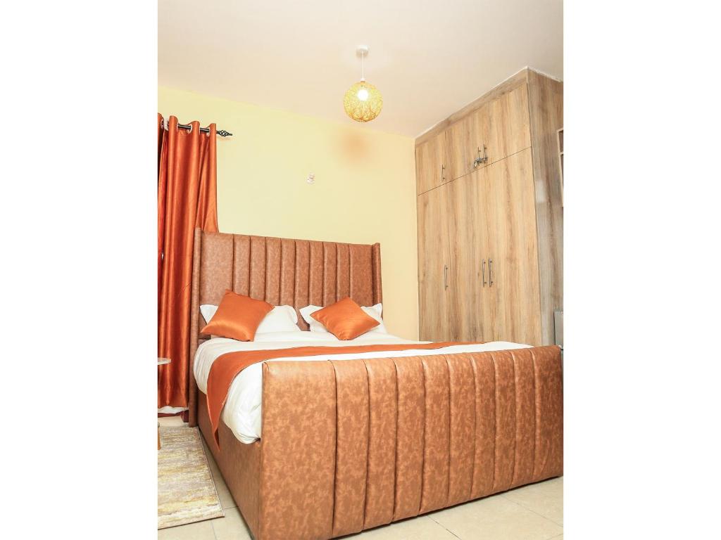 a bedroom with a large wooden bed with orange pillows at South Suites Studios in Nairobi