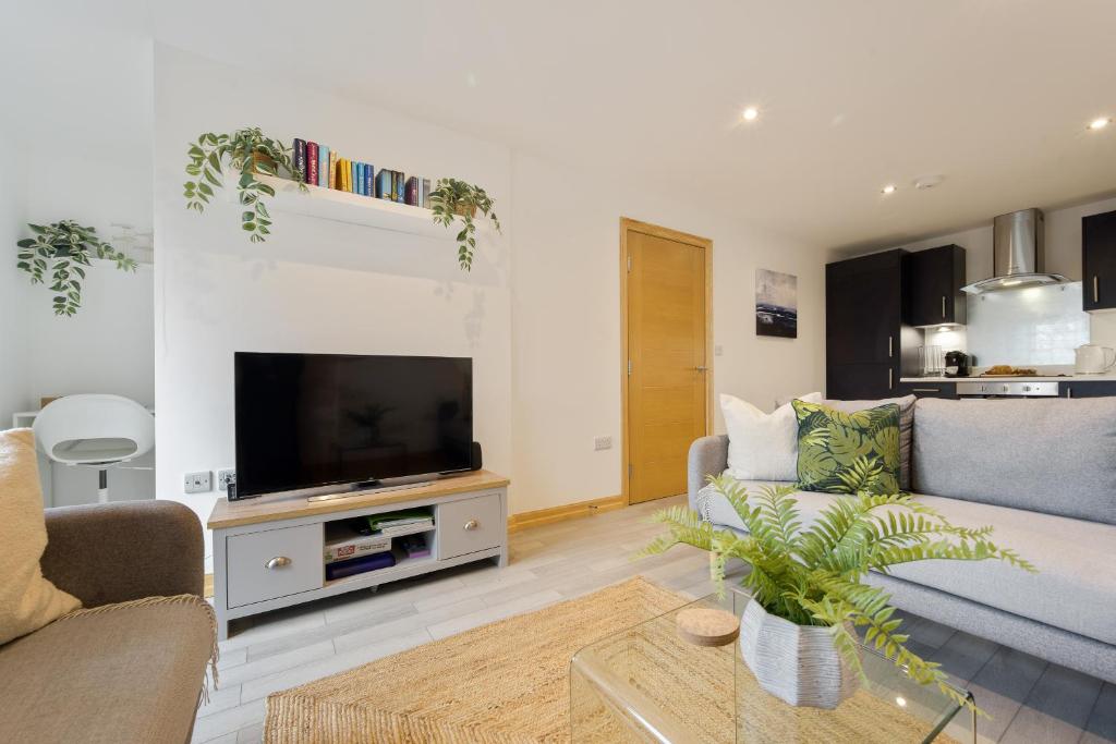 a living room with a couch and a flat screen tv at Large, newly renovated, three bedroom TOWN CENTRE split level apartment with free parking, sleeps seven - Walking distance to beach in Bournemouth