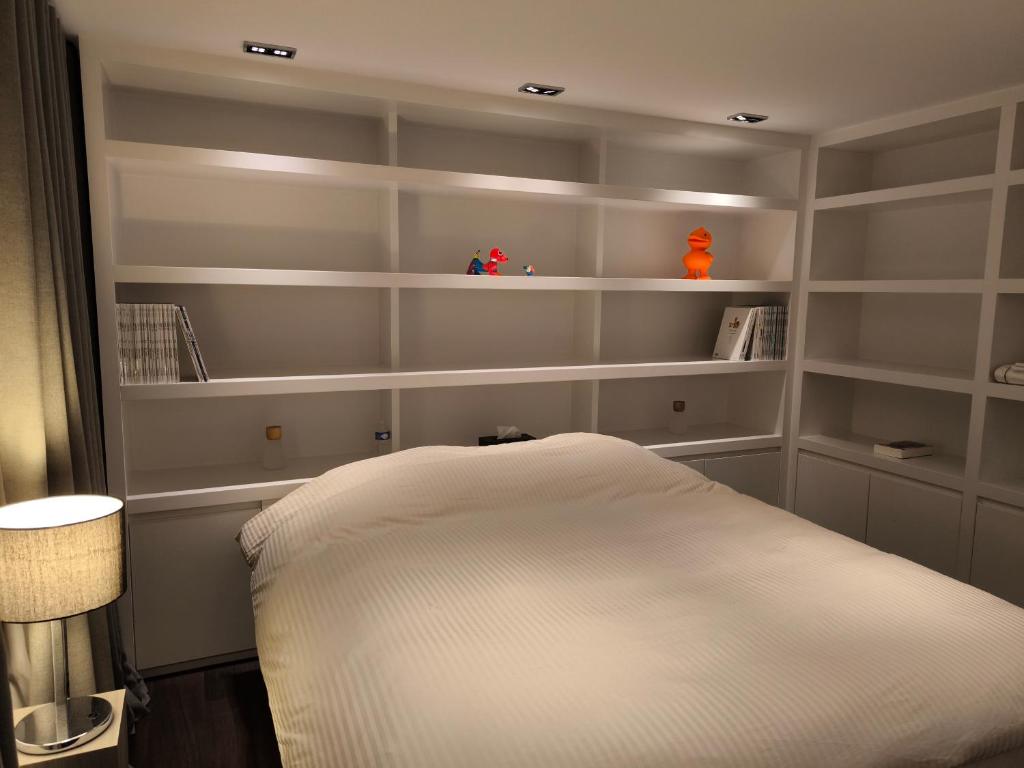 a bedroom with white shelves and a white bed at Vanbunnen in Knokke-Heist