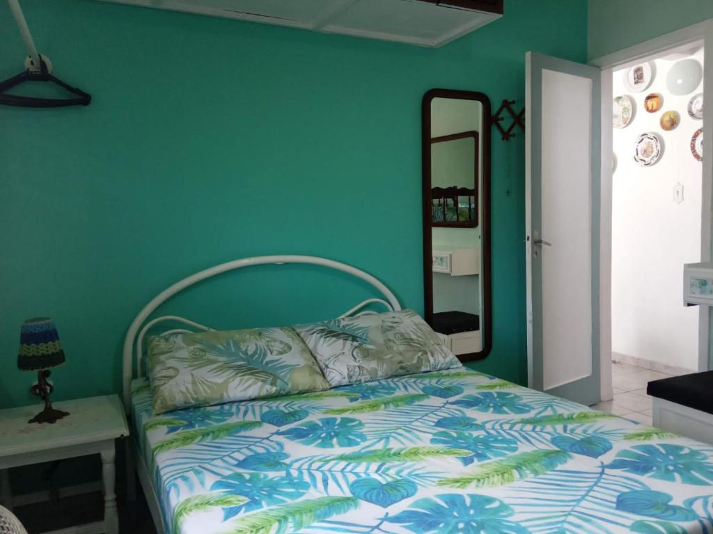 a bed in a room with a green wall at Apartamento Aconchego da vovó in Peruíbe