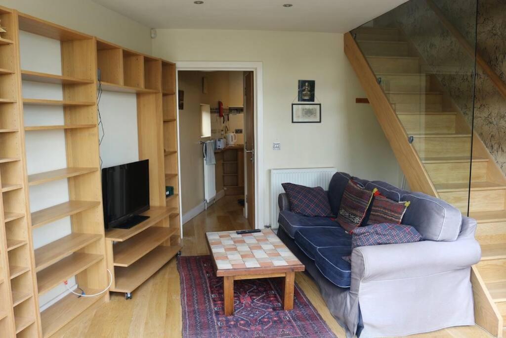 a living room with a couch and a tv and shelves at Stylish 1 Bedroom Flat in the heart of St Andrew's in Bristol