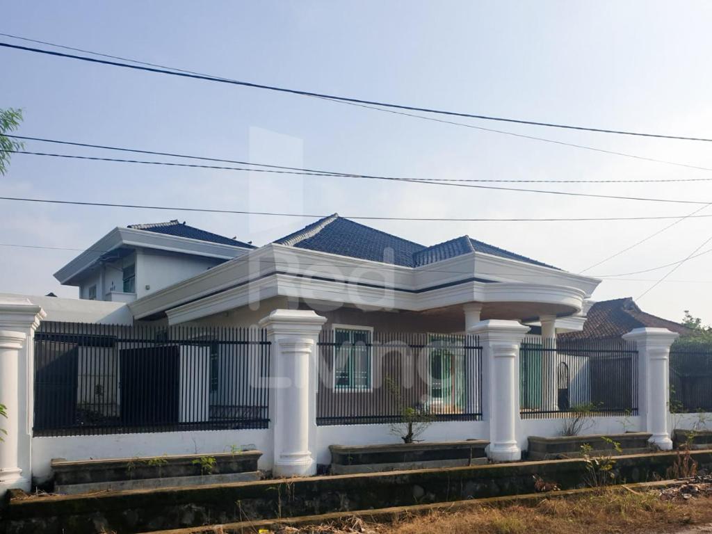 une maison blanche avec colonnes et clôture dans l'établissement Guest House Syariah Bunga Intan RedPartner, à Metro