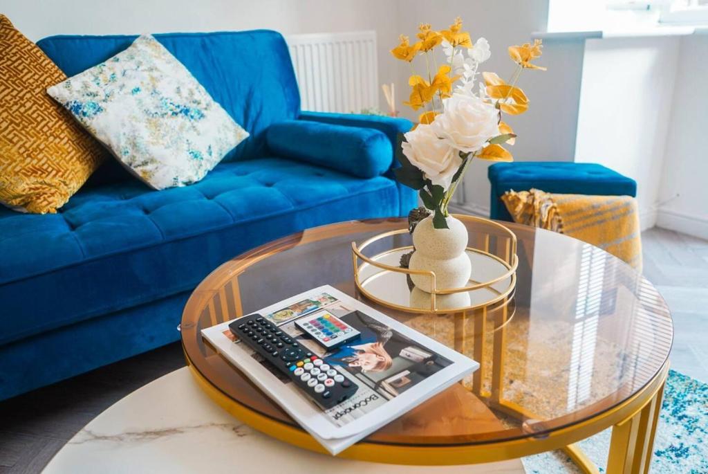 ein Wohnzimmer mit einem blauen Sofa und einem Glastisch in der Unterkunft Immaculate 4-Bed House in Kings Norton in Birmingham