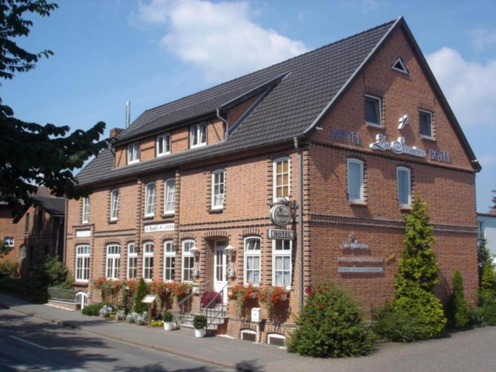 un grand bâtiment en briques rouges avec un toit noir dans l'établissement Hotel Zur Seemöwe, à Kirchdorf