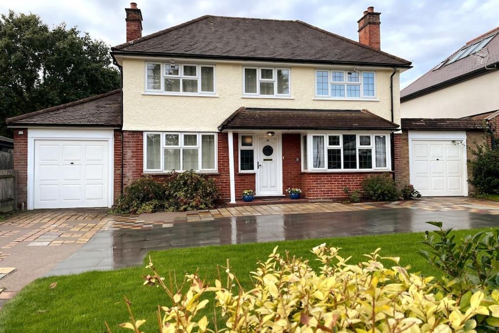 a house with two white garage doors in a yard at Spacious 3 bedroom house in heart of Hampton Court in East Molesey