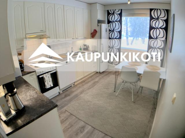 ケミにあるKaupunkikotiの白いキャビネット、テーブルと椅子付きのキッチンが備わります。