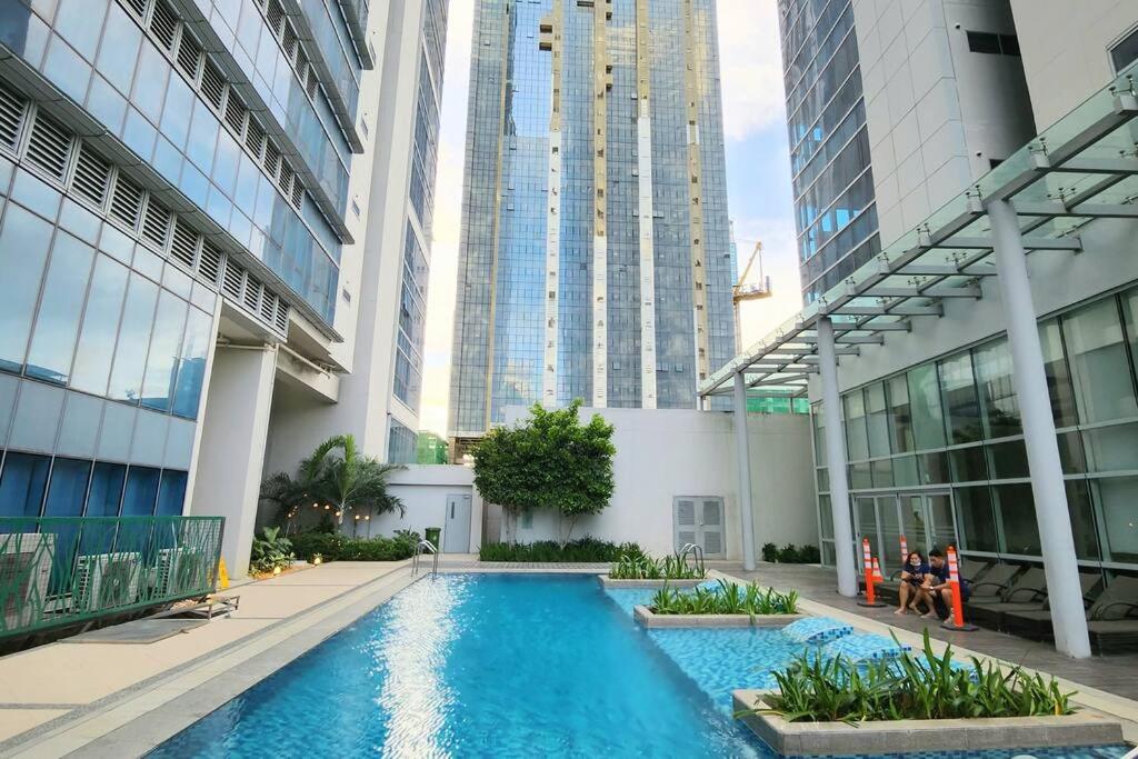une piscine au milieu d'un immeuble avec de grands bâtiments dans l'établissement BGC Cosy Spacious 1BR Uptown Parksuites with Balcony City View, à Manille