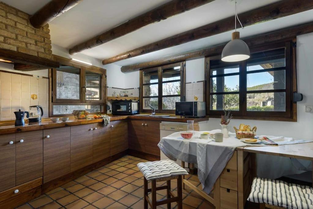 a kitchen with a table and some windows at Alojamiento la Atalaya de Araguas in Araguás del Solano