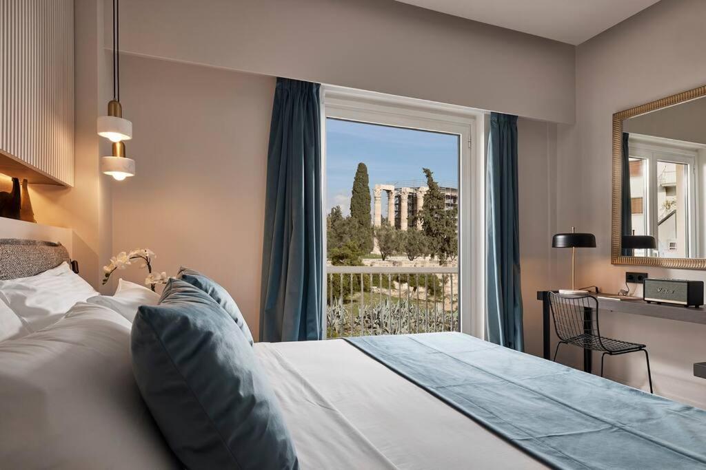 a bedroom with a bed and a large window at Acropolis Grand Suite in Athens