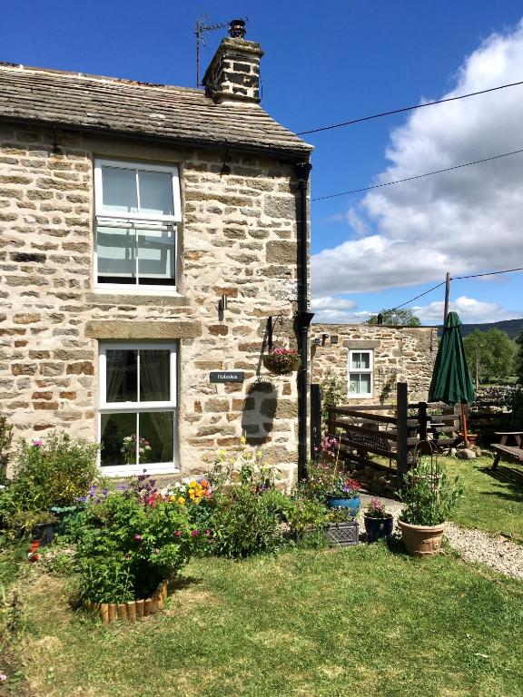 a stone house with a garden and a bench at Holmlea Cottage in Mickleton
