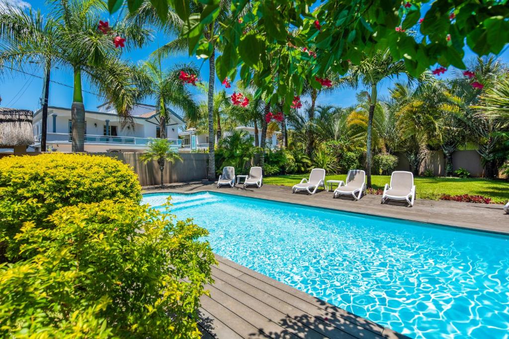 a swimming pool with lounge chairs and palm trees at Kisana Residence - Lovely 2 Bedroom Apartment - Pointe aux Canonniers in Pointe aux Cannoniers