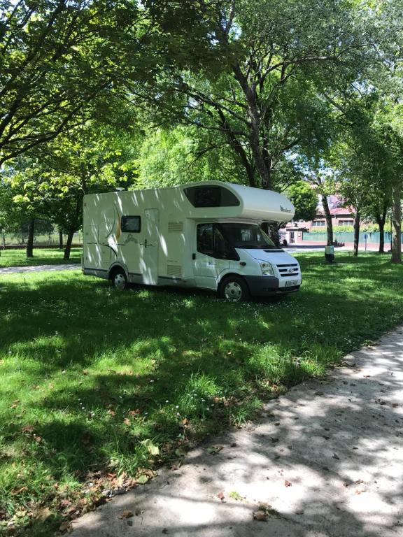 una caravana estacionada en el césped en un parque en Camping peregrino San marcos en Santiago de Compostela