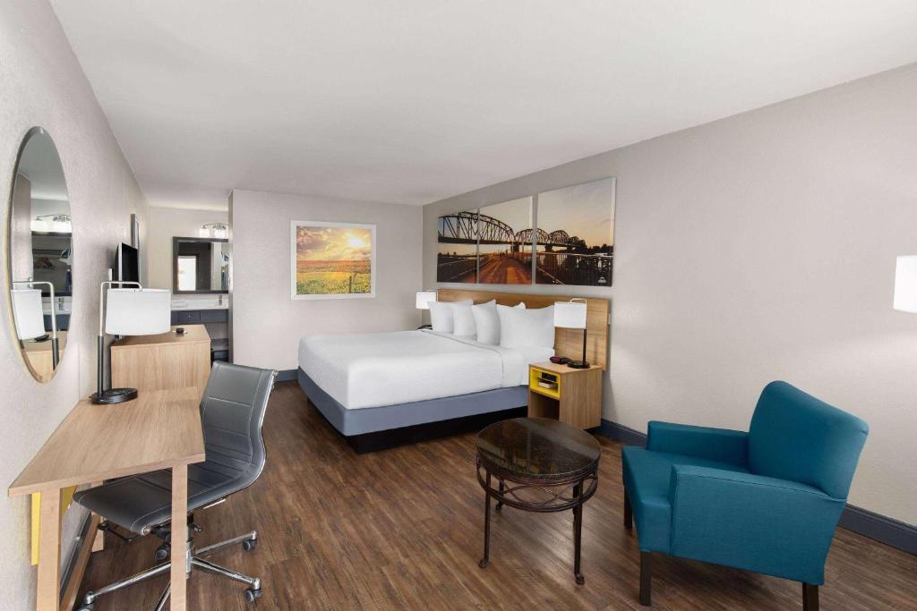 a hotel room with a bed and a desk and chairs at Days Inn by Wyndham Carlisle in Carlisle