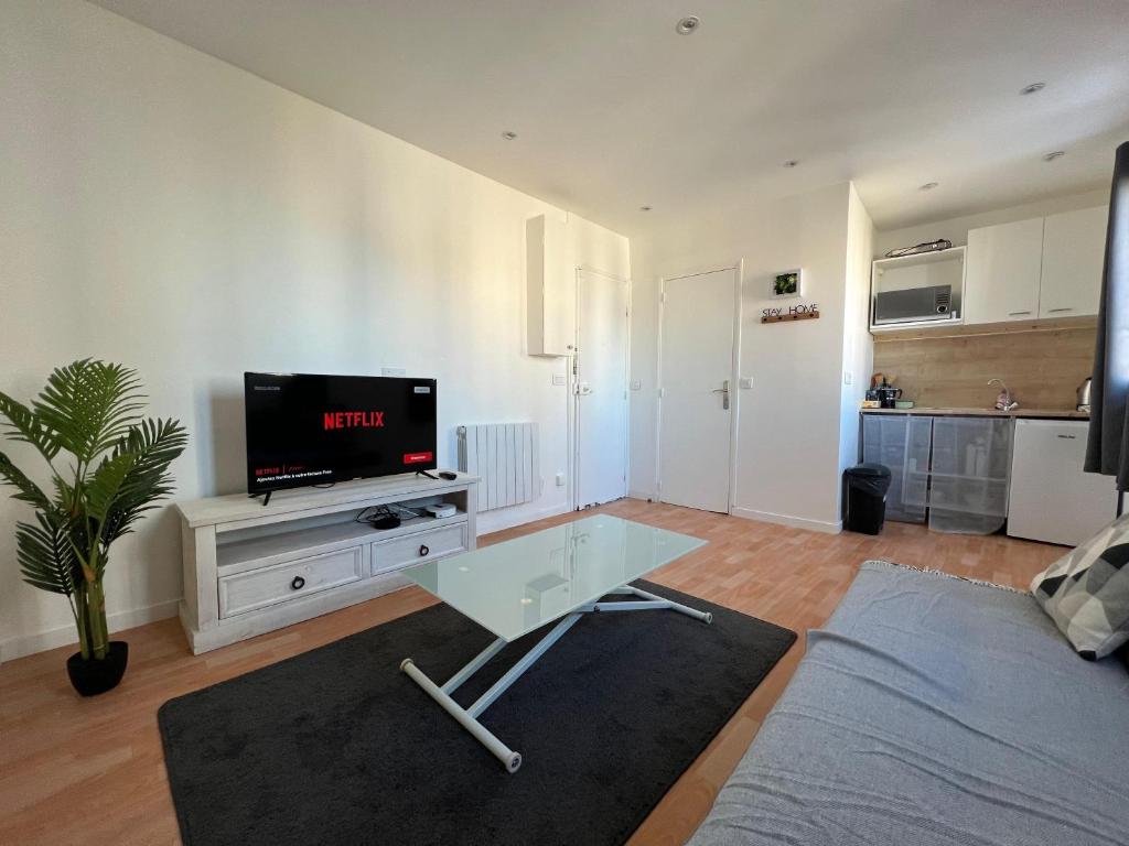 un salon avec une télévision à écran plat sur une table dans l'établissement Rue de la paix 3 personnes - 10'min Paris, aux Lilas