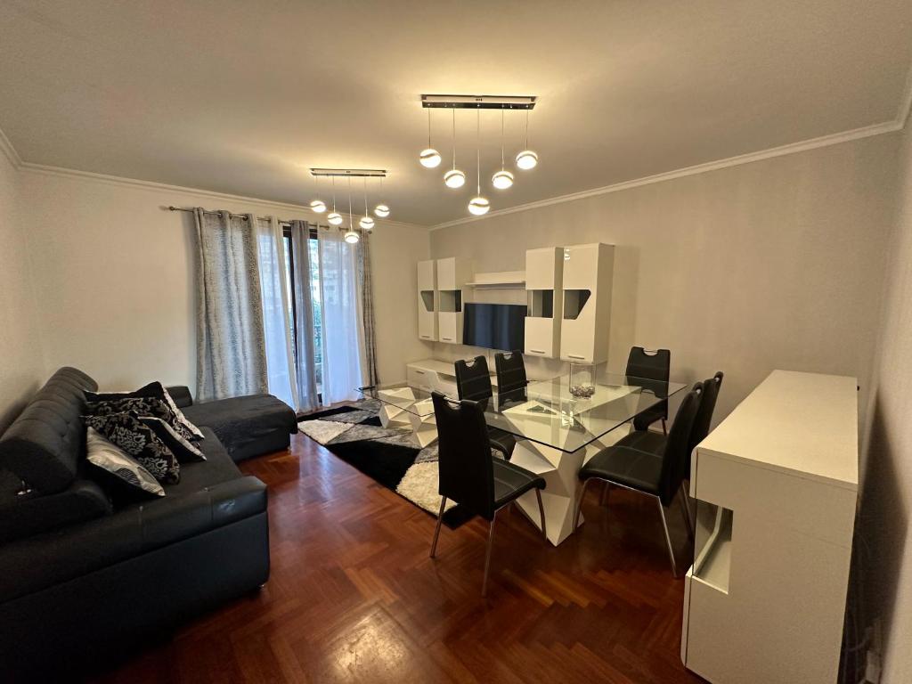 a living room with a glass table and a black couch at FUNCHAL APARTMENT WITH POOL - Garajau 2 in Caniço