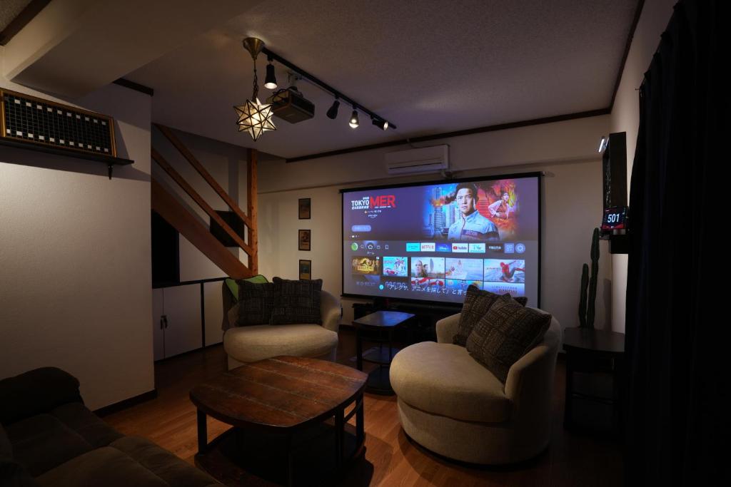 a living room with a large screen tv and chairs at CINEMA RESORTS 4 in Motobu