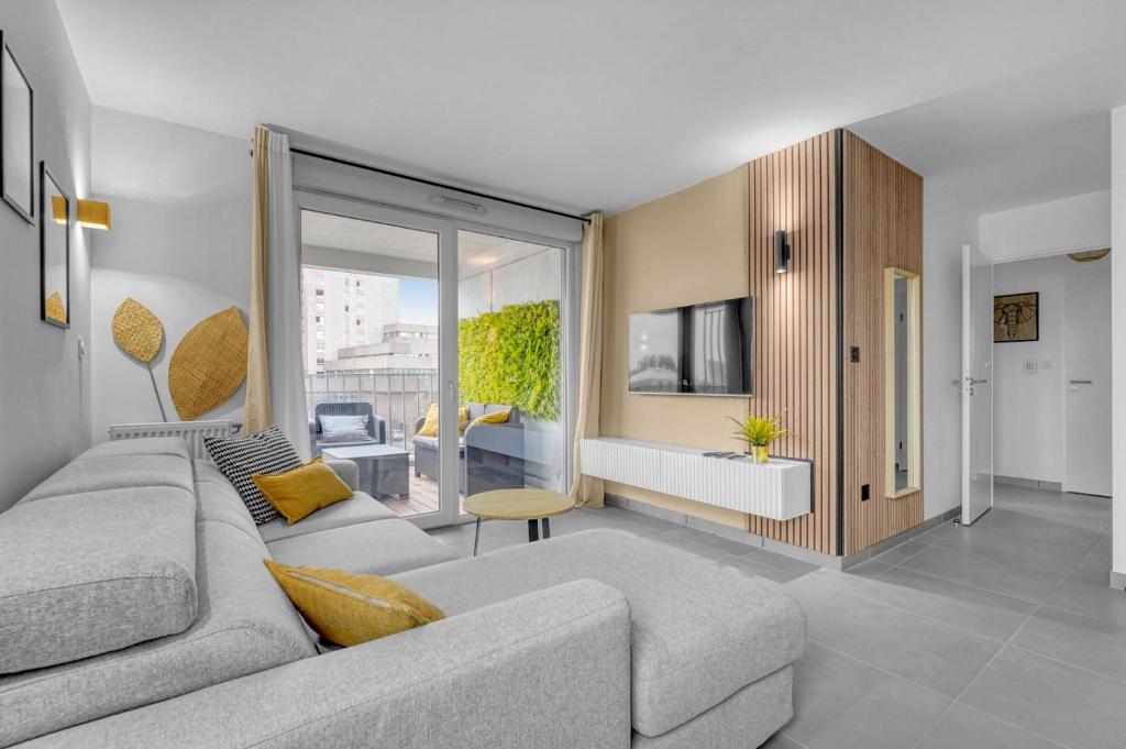 - un salon avec un canapé gris et une grande fenêtre dans l'établissement Perle Toulousaine, à Toulouse