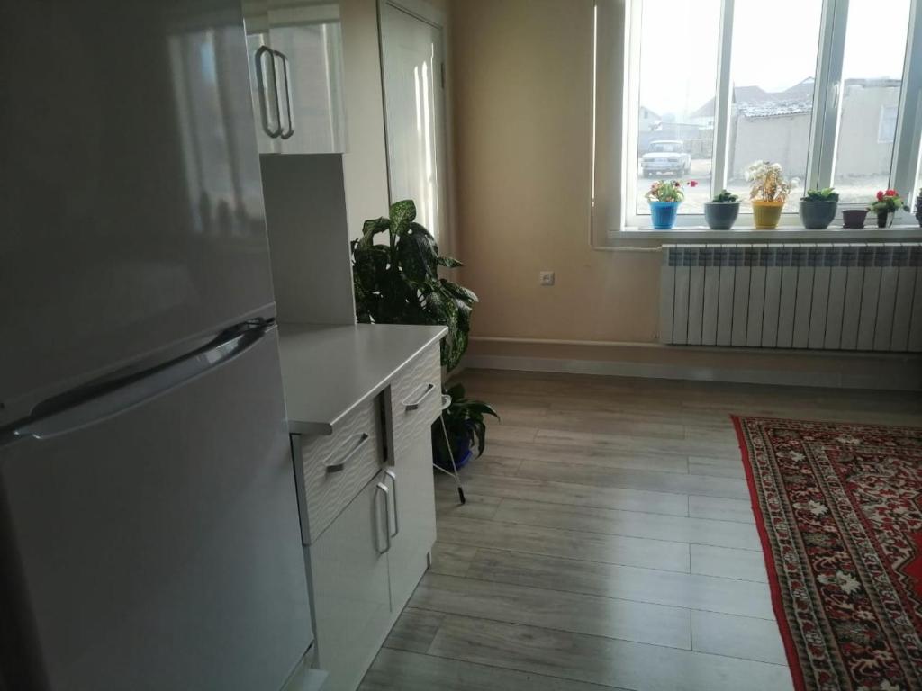 eine Küche mit weißen Schränken und Fenstern mit Topfpflanzen in der Unterkunft Гостевой дом (Hostel) in Kochkorka