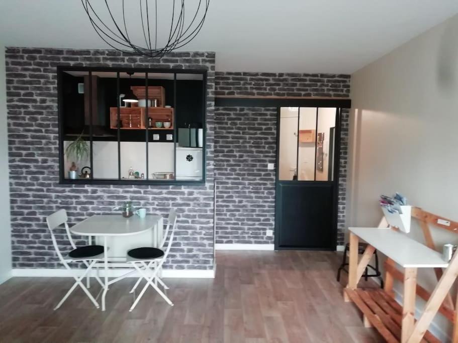 comedor con pared de ladrillo, mesa y sillas en Studio agréable dans résidence, en Joué-lès-Tours