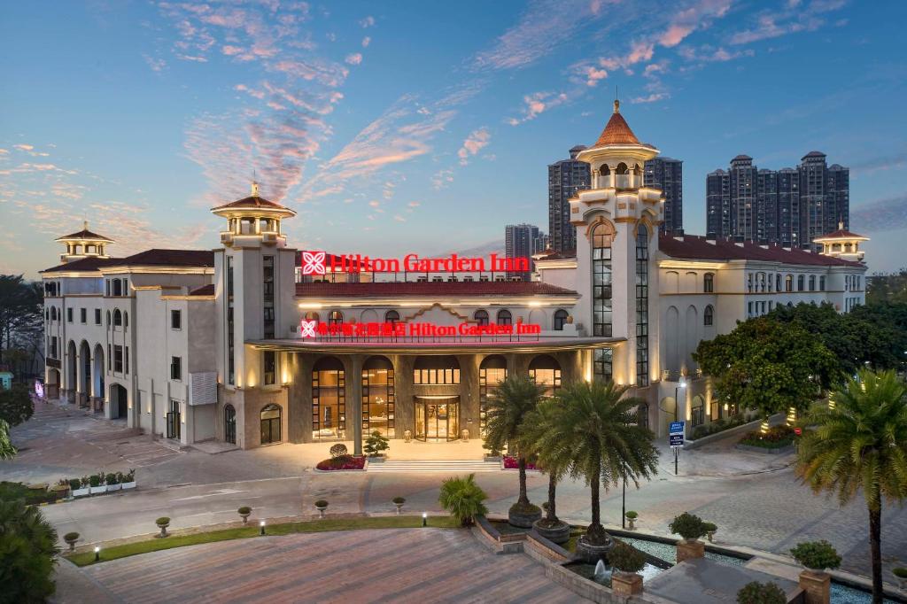 a large white building with a red sign on it at Hilton Garden Inn Huizhou North Railway Station in Huizhou