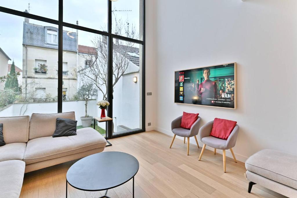 uma sala de estar com um sofá e cadeiras e uma televisão em Maison d'architecte à 15 min du centre de paris ! em Asnières-sur-Seine