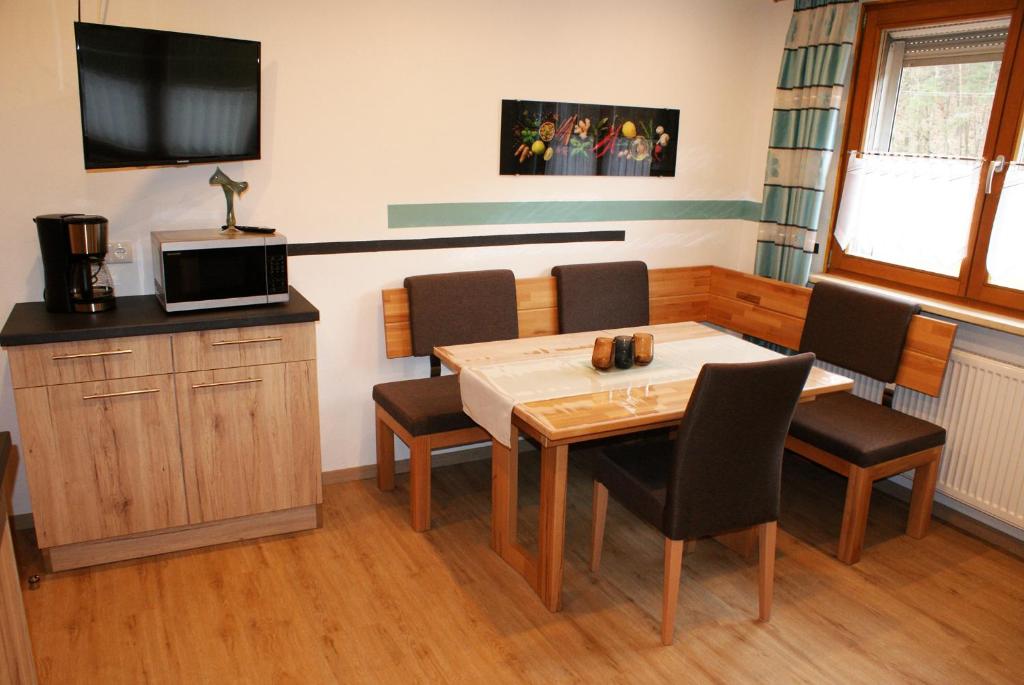 Pension Hessenmühle في Haundorf: غرفة طعام مع طاولة وكراسي وتلفزيون