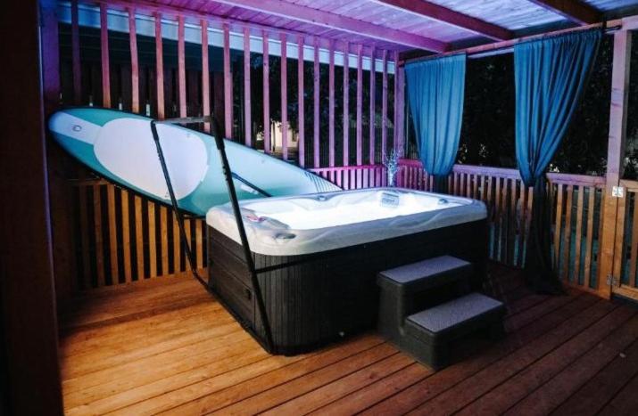 a bath tub with a surfboard on a deck at SEA HOUSE pool & jacuzzi, bikes, SUP - PRIVILEGE POINT camping & villas in Selce