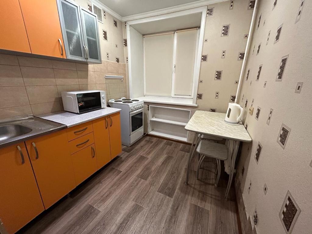 een kleine keuken met een wastafel en een magnetron bij Сеть BRAUN Сатпаева 11 in Pavlodar