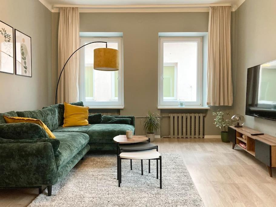 a living room with a green couch and a tv at 1840 Old Town Nook in Kaunas