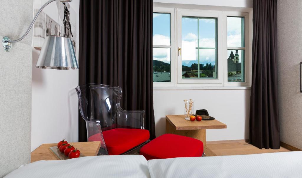 um quarto com uma cadeira vermelha e uma janela em Das Reisch em Kitzbühel