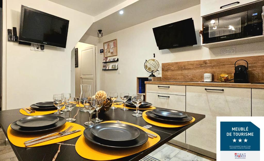 - une table avec des assiettes et des verres dans la cuisine dans l'établissement La Cloche Dorée, parking, 3 étoiles, en plein cœur de Fontainebleau, à Fontainebleau