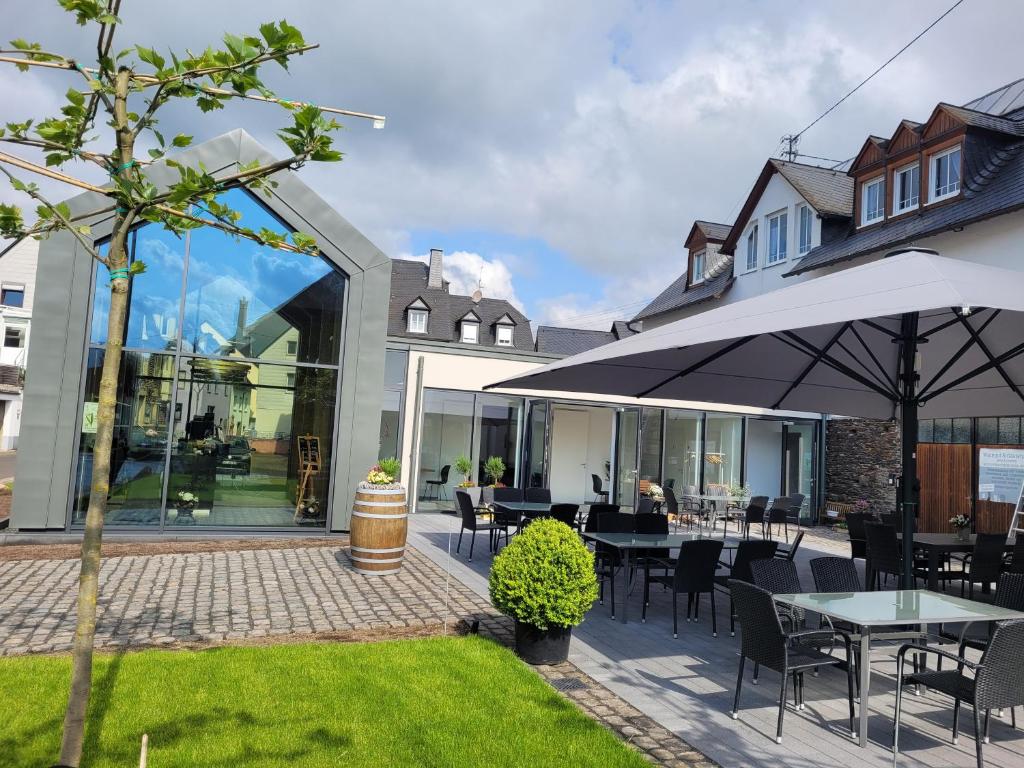 eine Terrasse mit Tischen, Stühlen und einem Sonnenschirm in der Unterkunft Gästehaus Kiebel in Lösnich