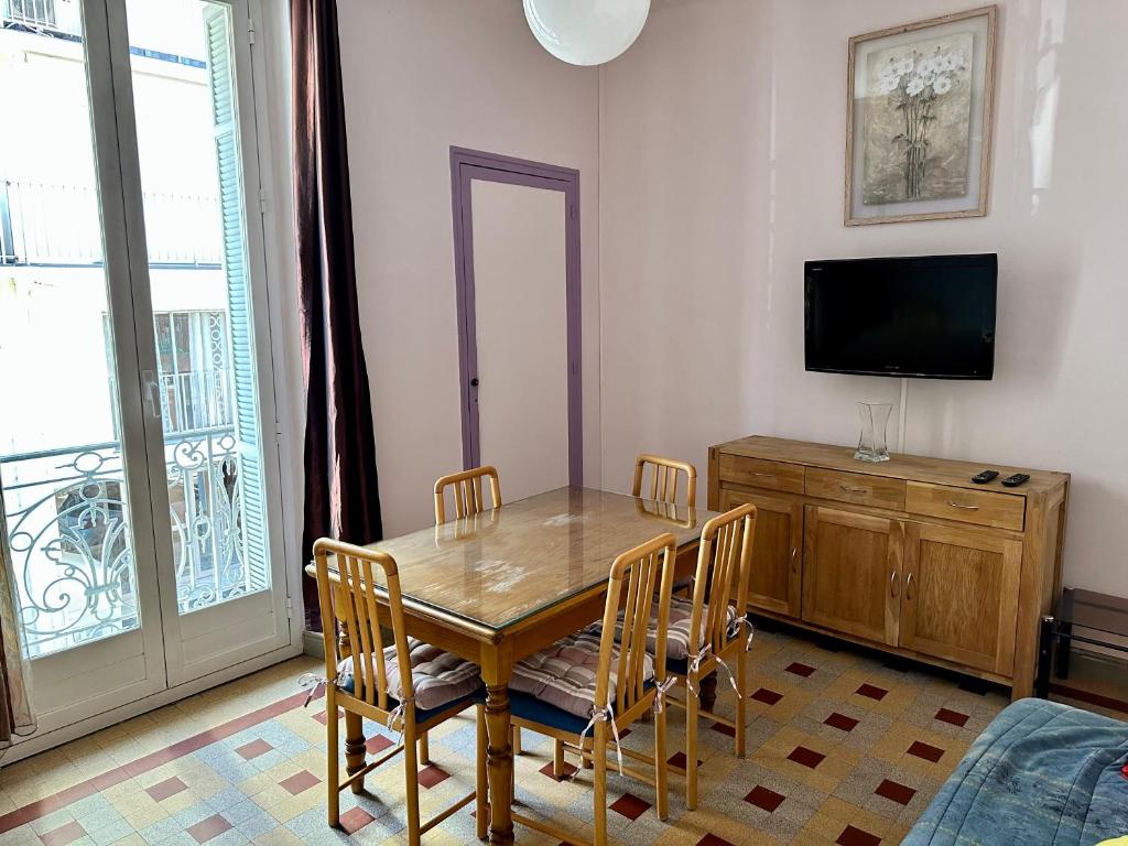 a dining room with a table and chairs and a television at APPARTEMENT MAISON, CENTRE VILLE, PROCHE PLAGE TOUT COMMERCE in Menton