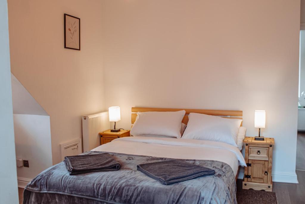 ein Schlafzimmer mit einem Bett mit zwei Lampen an zwei Tischen in der Unterkunft Spacious Flat with Free Parking in Harrogate