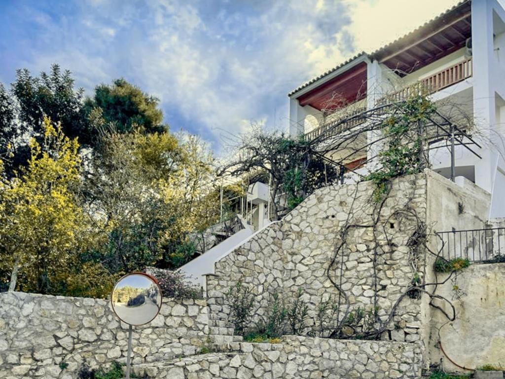 a house with a stone wall and a staircase at Casa Bianca Elegant House Near Beach in Spetses