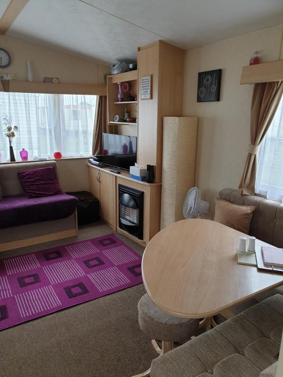 a living room with a table and a couch at 3 bed static caravan in Chapel Saint Leonards